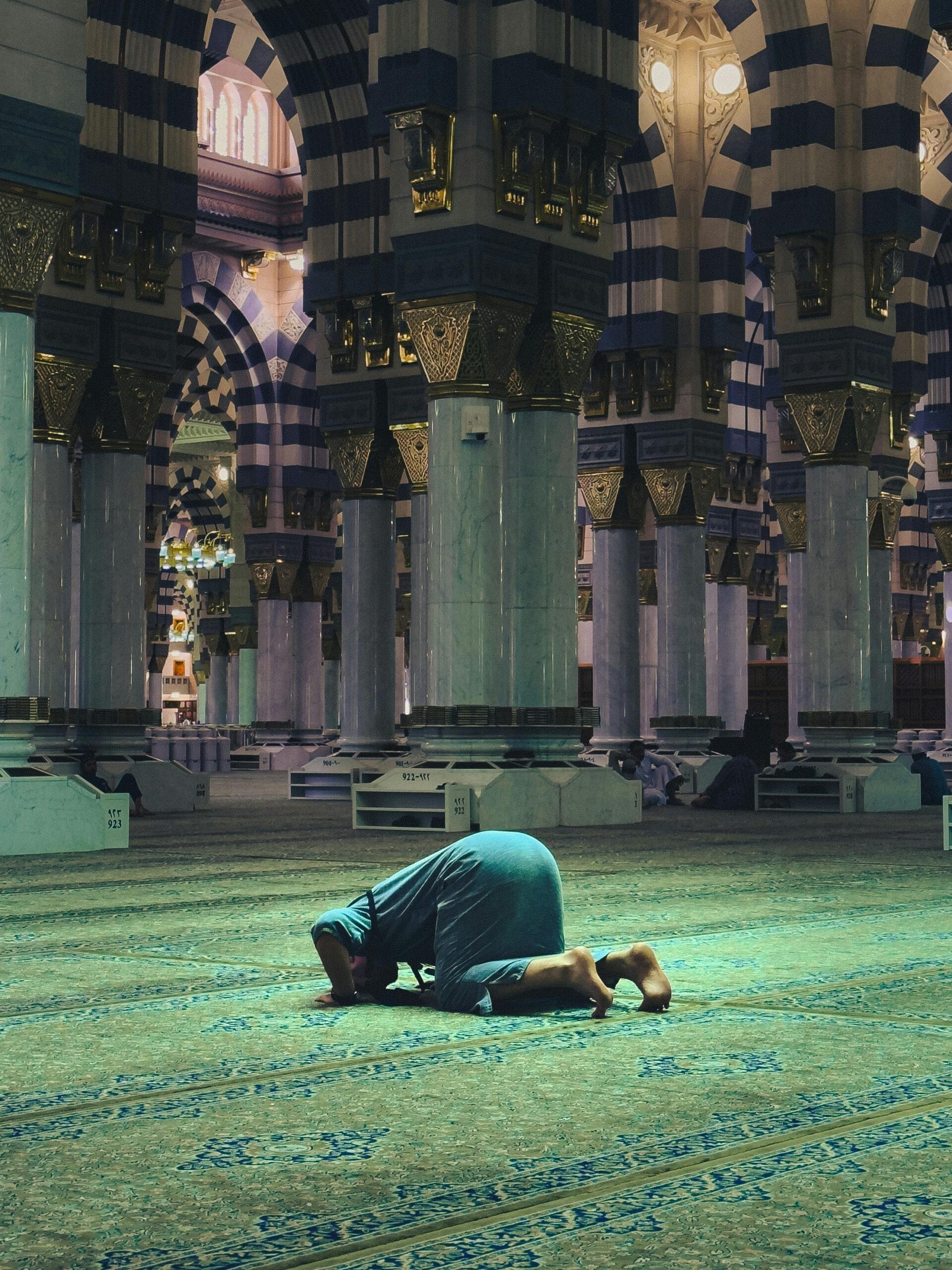 A person praying inside the historic Al-Masjid an-Nabawi, Medina, Saudi Arabia.