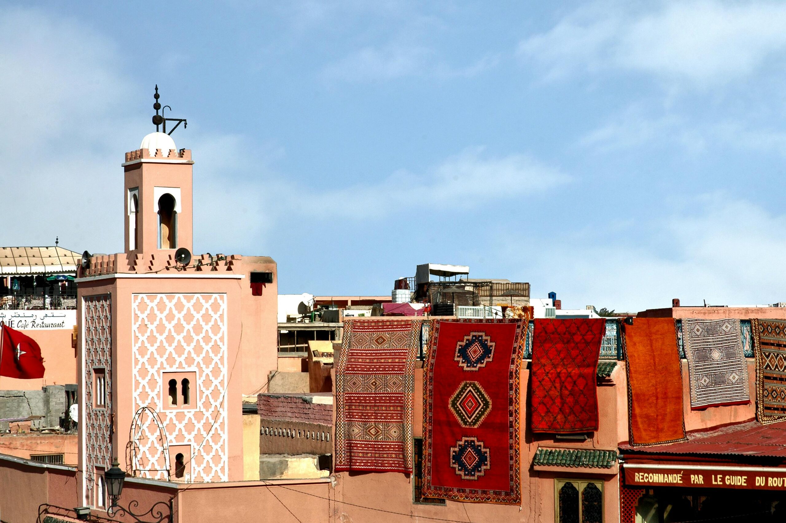 Colorful Moroccan rugs on a rooftop with traditional architecture in Marrakech, Morocco.