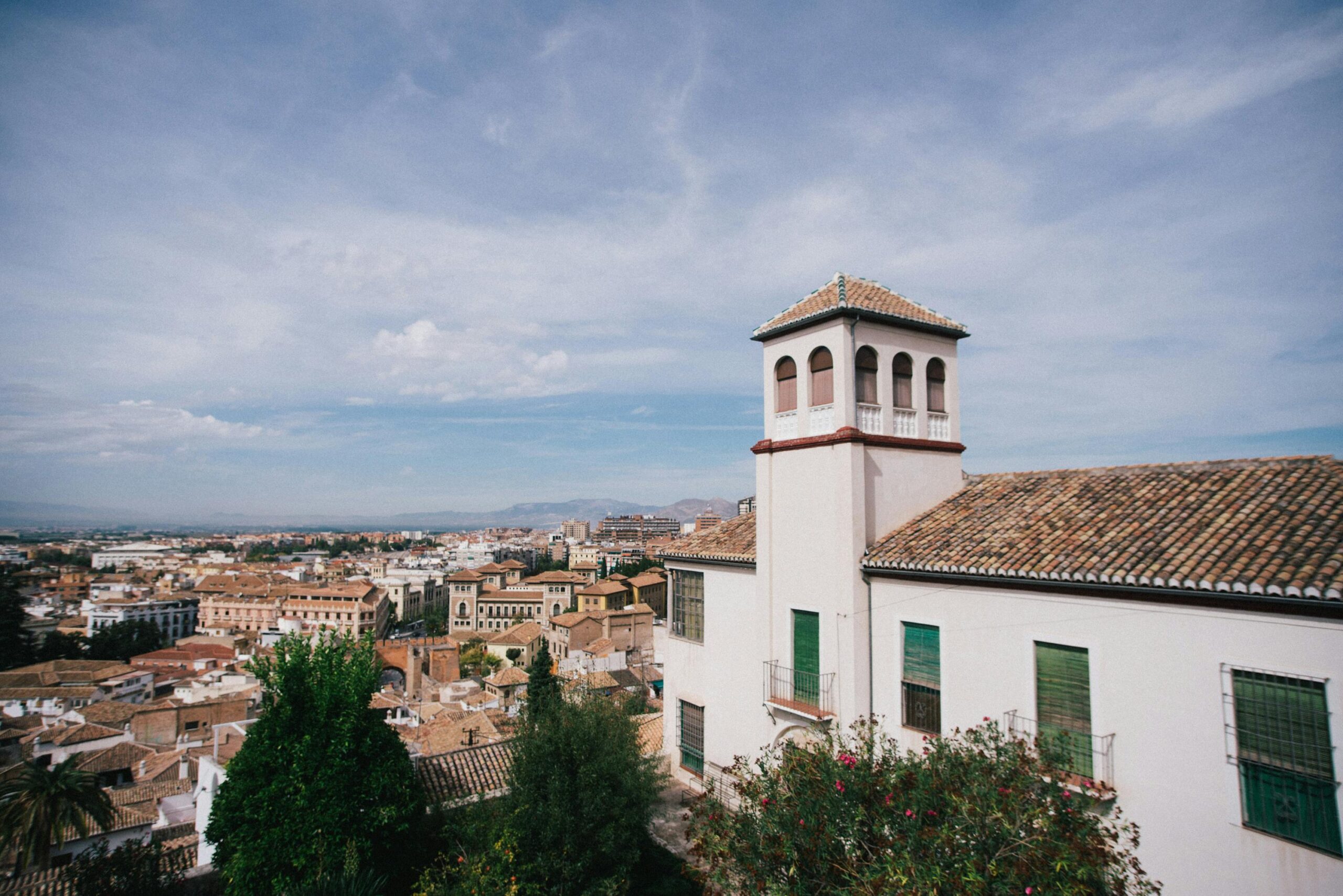 A panoramic view of Granada's traditional architecture and tiled roofs under a blue sky.