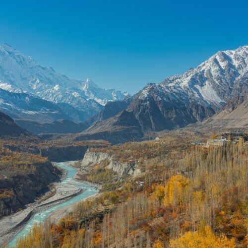 Stunning aerial view of Hunza Valley in autumn with snow-capped mountains and a winding river.