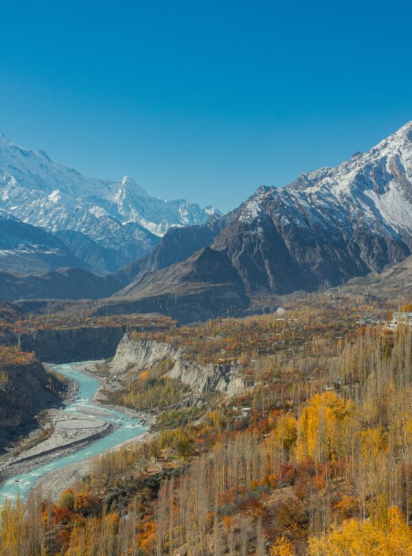 Stunning aerial view of Hunza Valley in autumn with snow-capped mountains and a winding river.