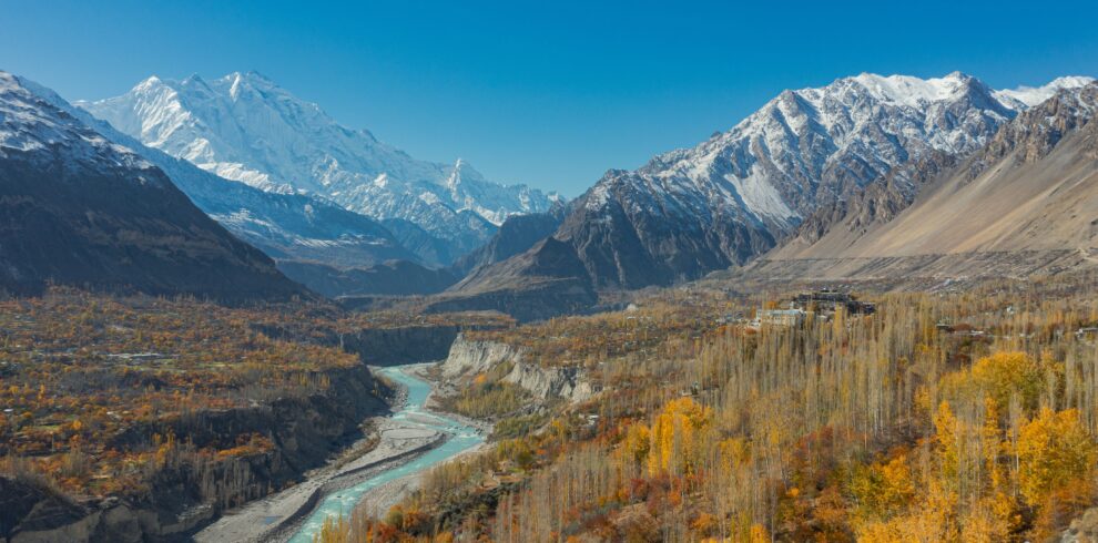 Stunning aerial view of Hunza Valley in autumn with snow-capped mountains and a winding river.