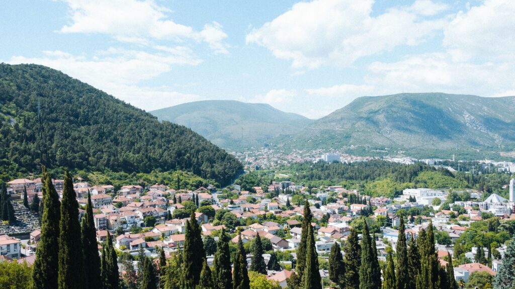 Stunning aerial view of Mostar city surrounded by lush hills and forest.