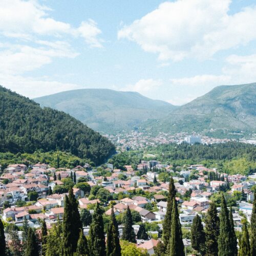 Stunning aerial view of Mostar city surrounded by lush hills and forest.