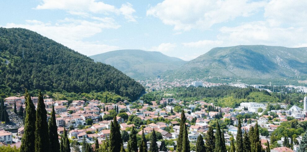 Stunning aerial view of Mostar city surrounded by lush hills and forest.