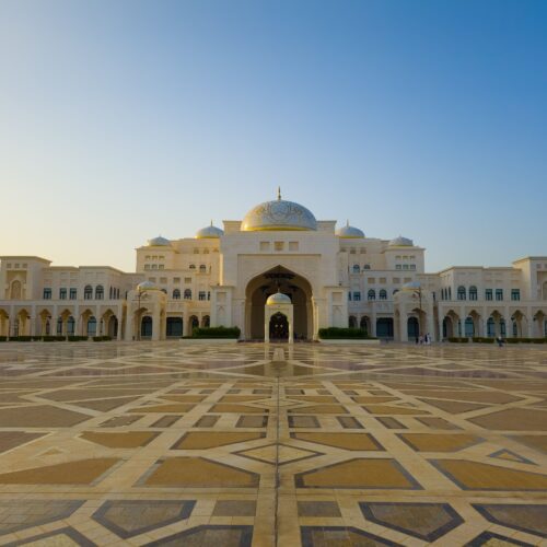 Stunning view of a grand Islamic architectural building with ornate domes at sunset.