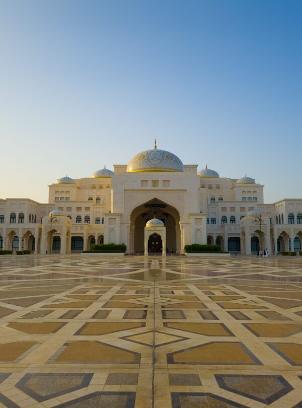 Stunning view of a grand Islamic architectural building with ornate domes at sunset.