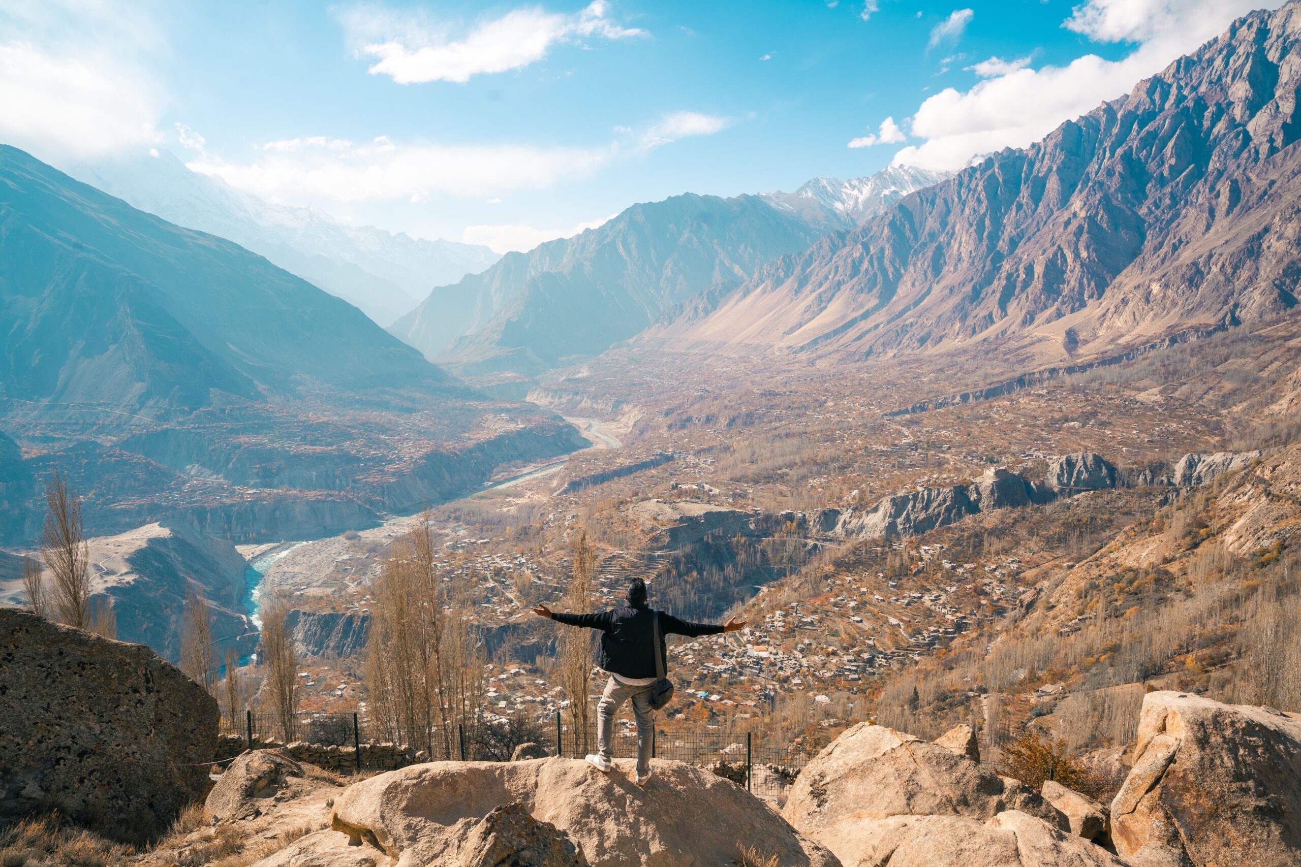 A traveler enjoying a breathtaking view of Hunza Valley, Karakoram Mountains, Pakistan.