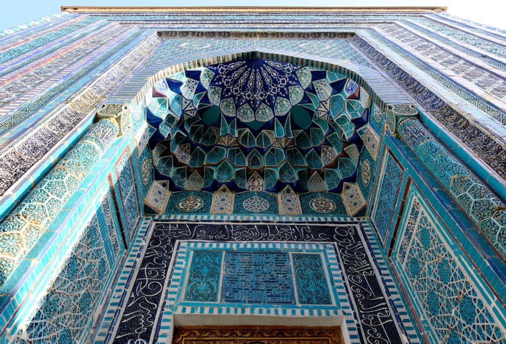 Close-up of intricate blue and turquoise Islamic tiles on a building facade.