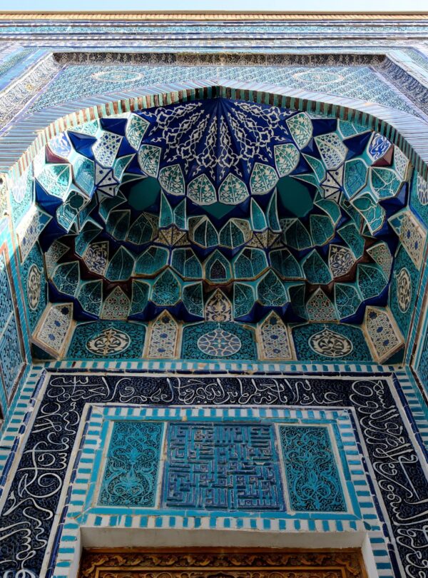 Close-up of intricate blue and turquoise Islamic tiles on a building facade.