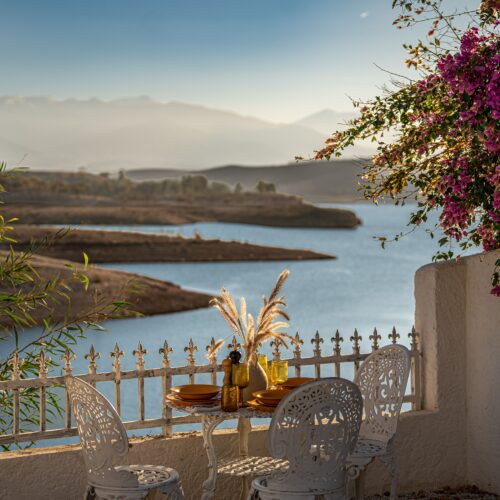 Charming outdoor dining scene with colorful flowers and serene lake view at sunset.