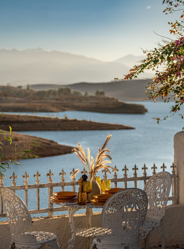 Charming outdoor dining scene with colorful flowers and serene lake view at sunset.