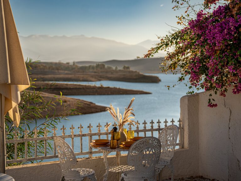 Charming outdoor dining scene with colorful flowers and serene lake view at sunset.